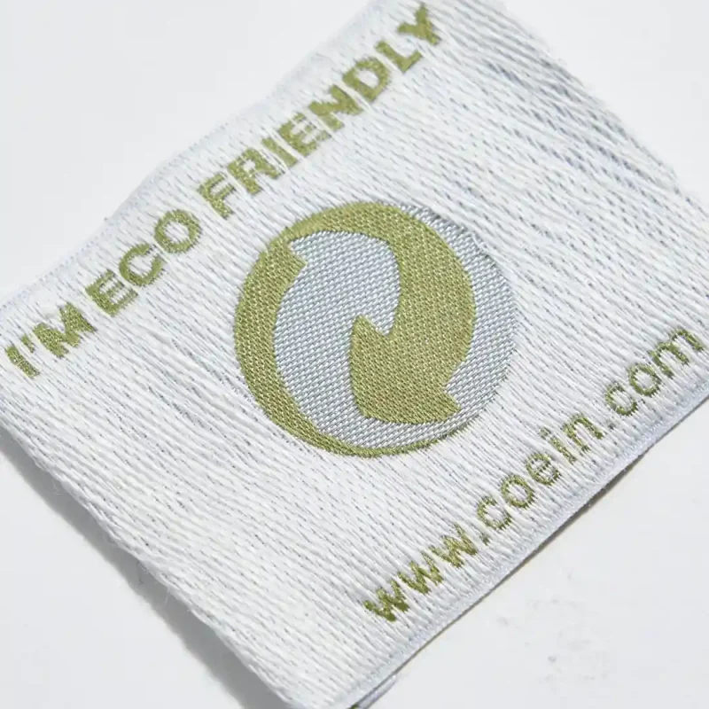 Etichetta tessuta con fondo in canapa, design eco-friendly per abbigliamento e accessori.